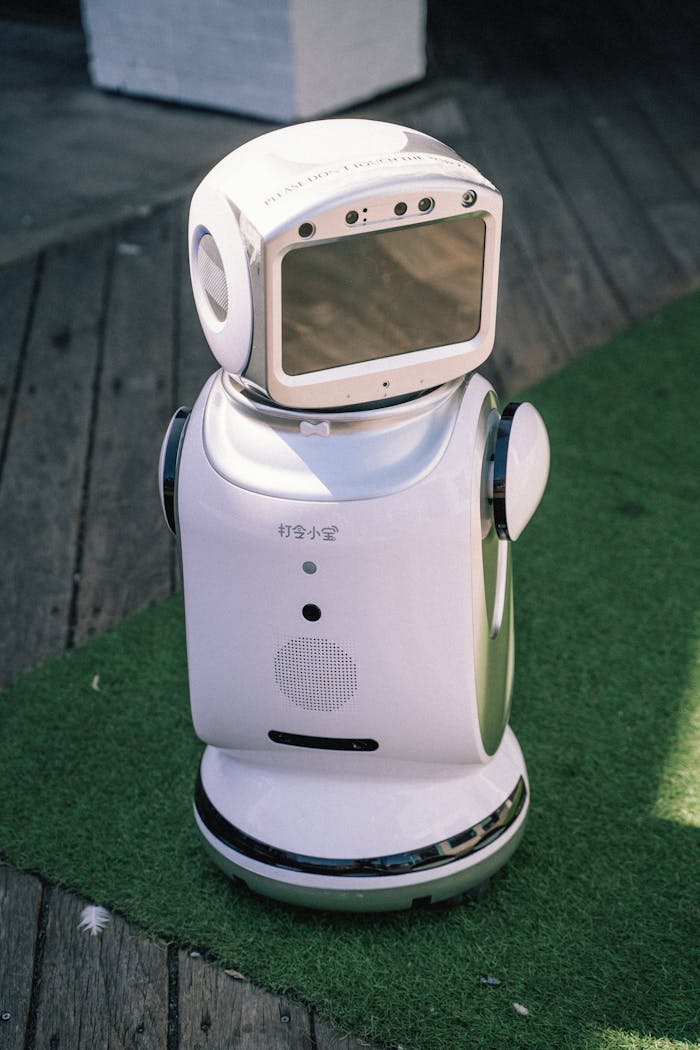 about-01 A modern robot stands on grass and wooden flooring, showcasing cutting-edge technology.